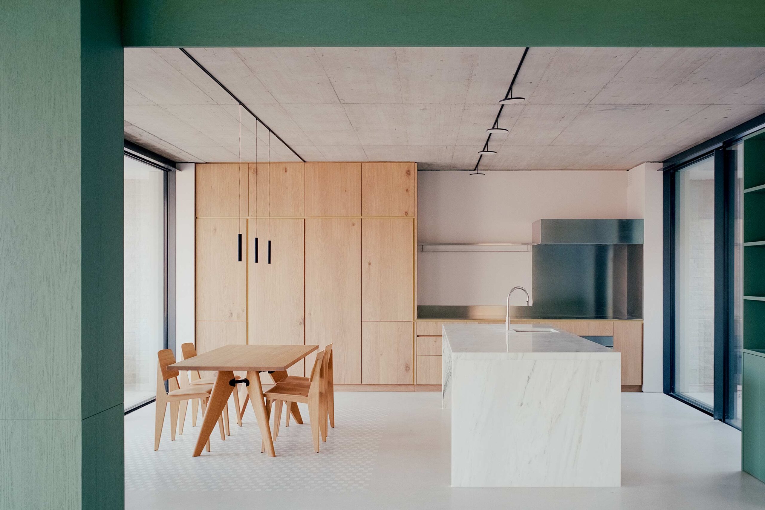 The original rough concrete ceiling is contrasted with a refined kitchen material palette of marble and oak.